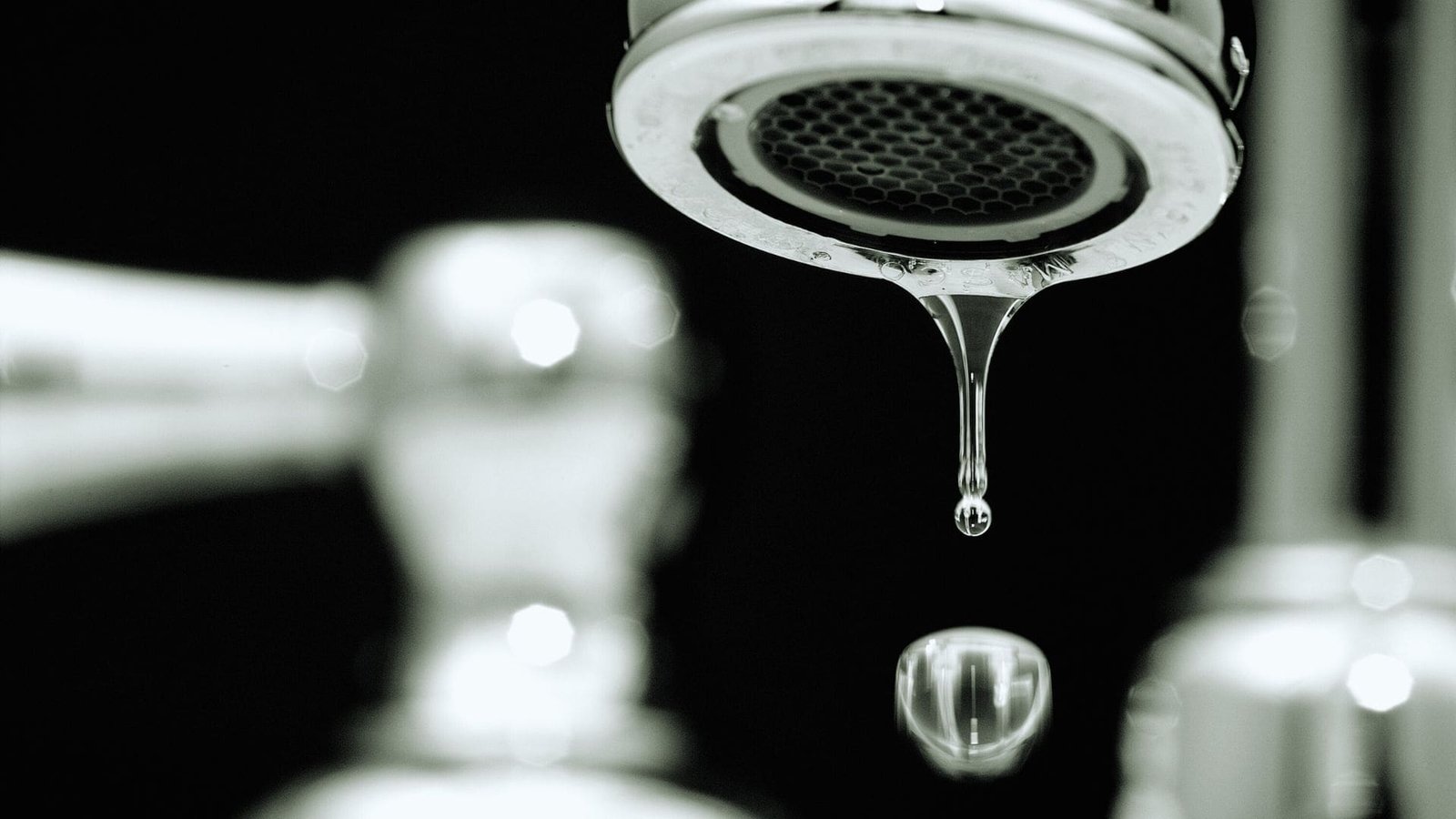 A shimmering drop of water clinging to a faucet, symbolizing a small but persistent leak.

