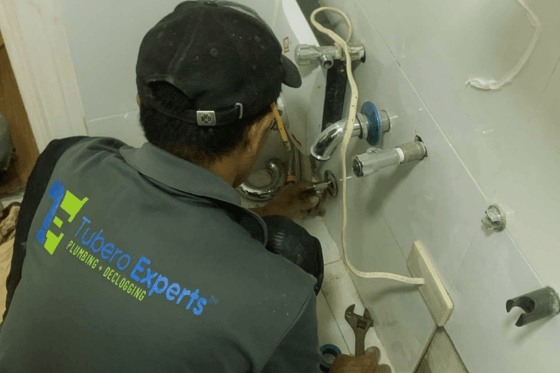 Plumber repairing leak in kitchen – plumbing services by Tubero Experts