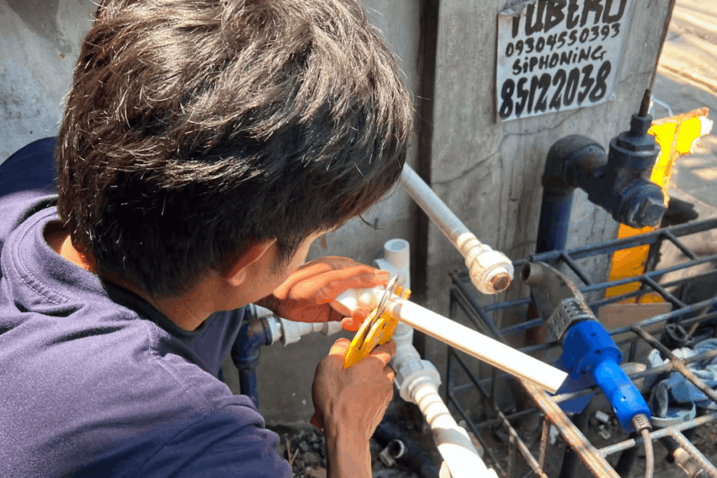 Tubero Experts plumber cutting a PVC pipe during a repair job in BGC.