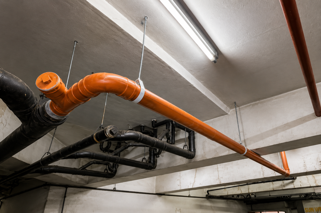 Completed sanitary line pipe installed and secured along a ceiling after a leak repair job.