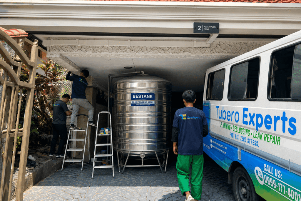 Water tank installation team setting up a new stainless steel tank at a home
