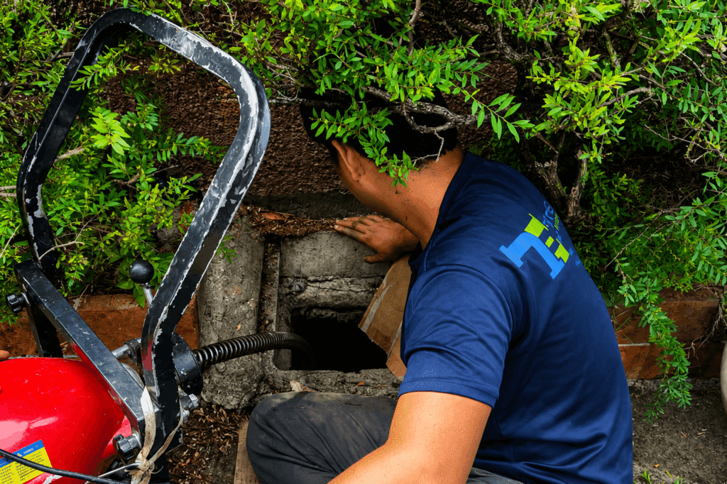 Tubero Experts plumber inspecting an outdoor drain opening before declogging service