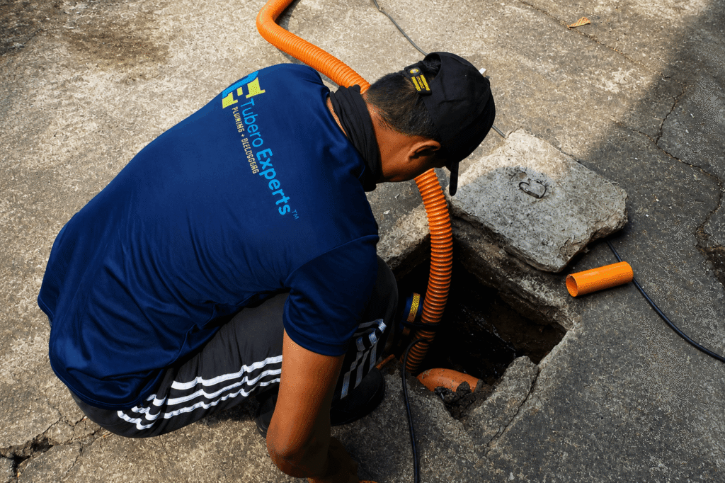 Tubero Experts plumber siphoning a septic tank through a street access point