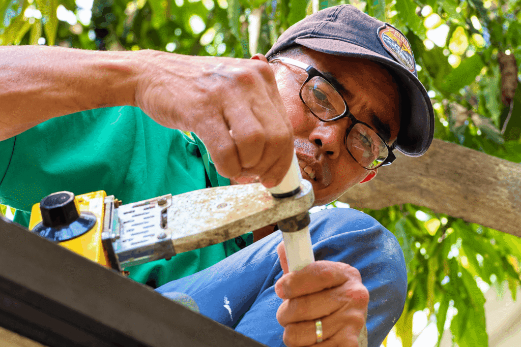Plumber using crimping tool for water leak repair on PVC pipe