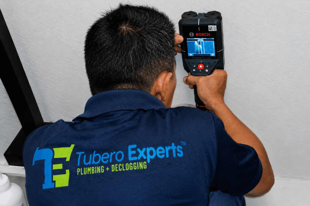 Tubero Experts plumber using a Bosch detection device to perform non-invasive leak detection service on a wall