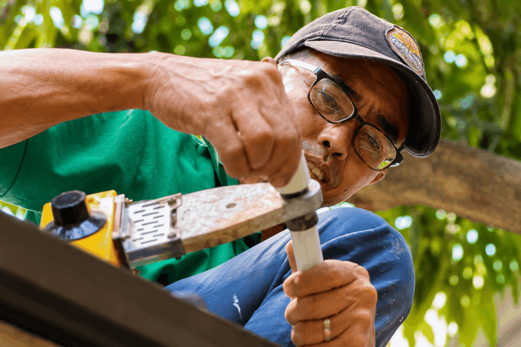 echnician fitting a PVC pipe with a hand tool outdoors" Title: "Precision Pipe Fitting