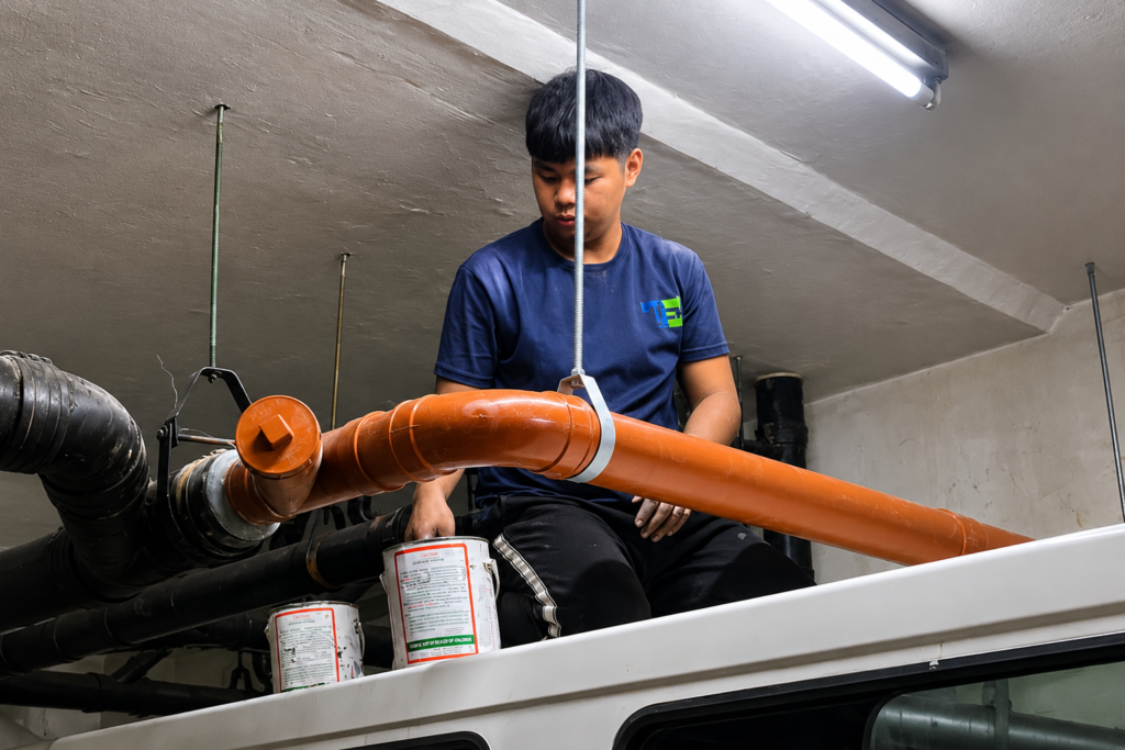 Tubero Experts plumber fitting orange PVC sanitary line piping as part of a leak repair job.Careful measuring and fitting ensures the sanitary line connects clean and tight after every repair.