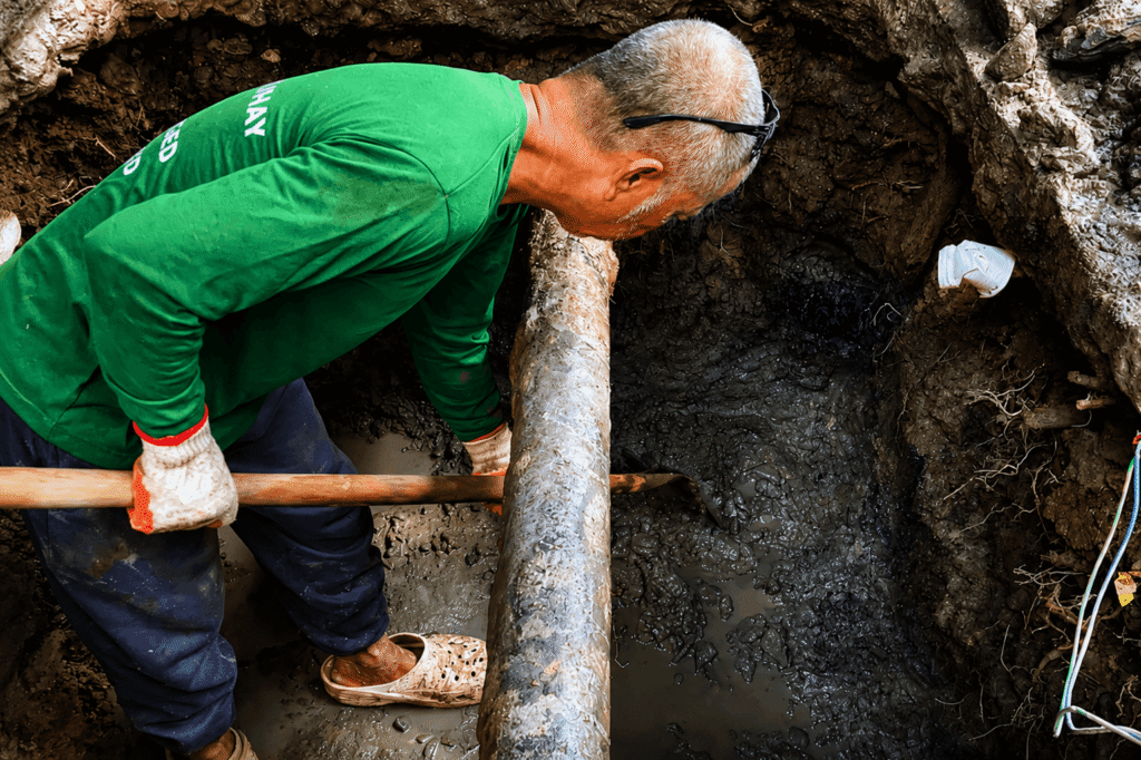 Tubero Experts technician inspecting an excavated septic tank pipe connection