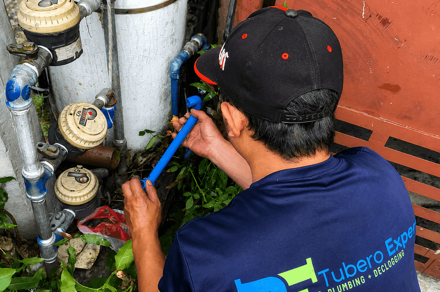 Tubero Experts plumber repairing and replacing water line connections at an outdoor pipe and meter cluster