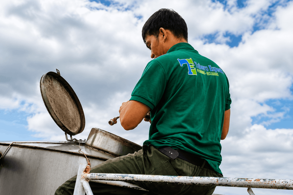 Water tank troubleshooting technician opening a tank lid for inspection