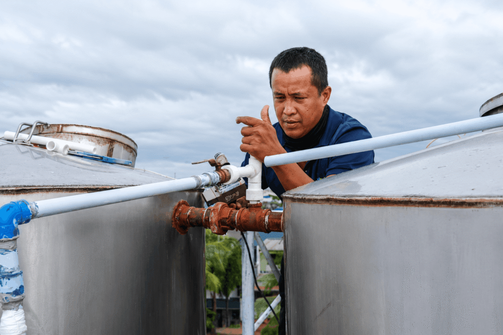 Water tank troubleshooting technician connecting pipework between two tanks