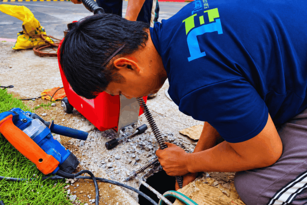 Tubero Experts plumber clearing an outdoor drain with a drain cleaning machine