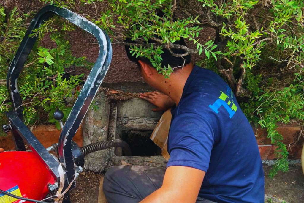 Technician using a drain machine at an outdoor drain access point