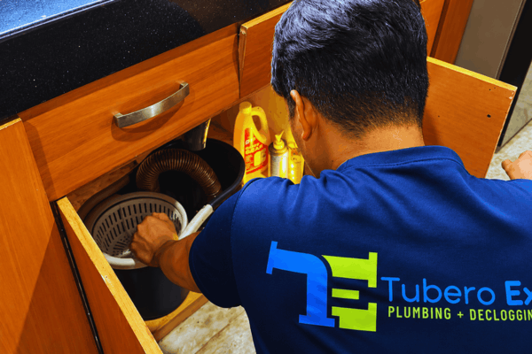 Tubero Experts plumber checking the drain pipe under a kitchen sink