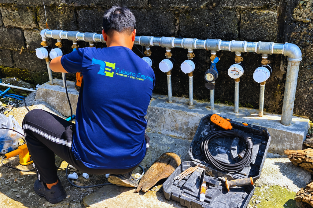 Tubero Experts technician installing water meters along a metal pipe line