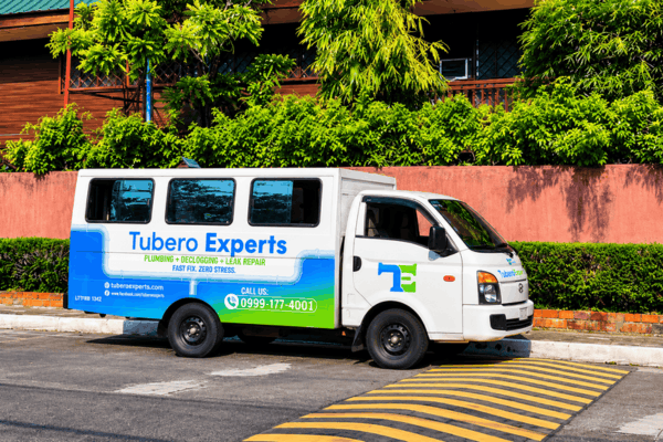 Tubero Experts van with plumbing and declogging branding parked by a pink wall